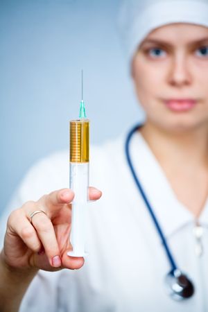 Doctor holding big syringe with yellow liquid, focus on syringeの写真素材