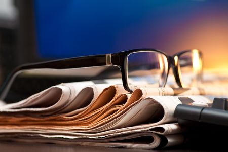 Glasses on stack of newspapers, very shallow focusの写真素材