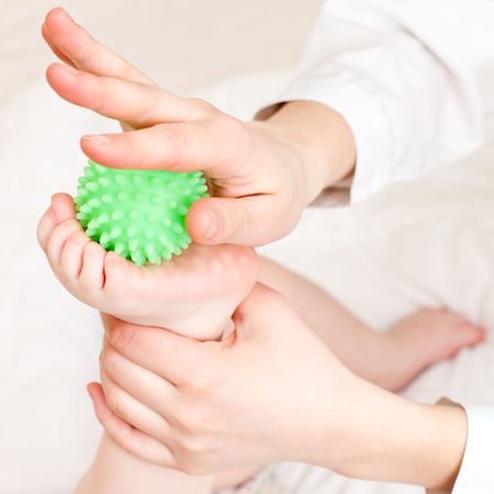 Masseur massaging child's foot with rubber device, shallow focusの写真素材