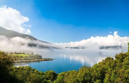 Clouds over Lake Rotoaria, New Zealand. Dots on water surface are swansの写真素材