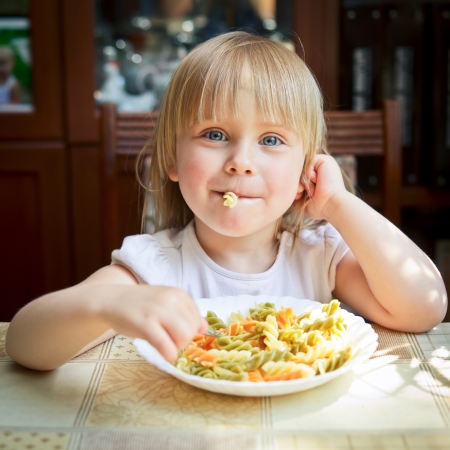 Cute little girl eating Fusilliの写真素材