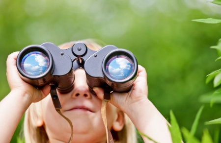 Little girl looking through binoculars outdoorsの写真素材