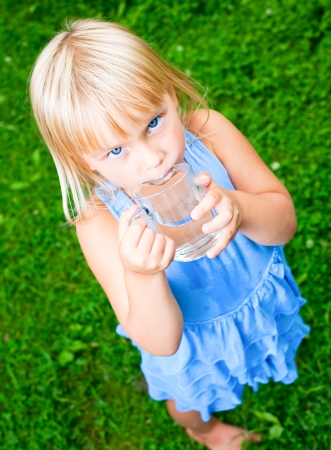 Cute little girl drinking water outdoorsの写真素材
