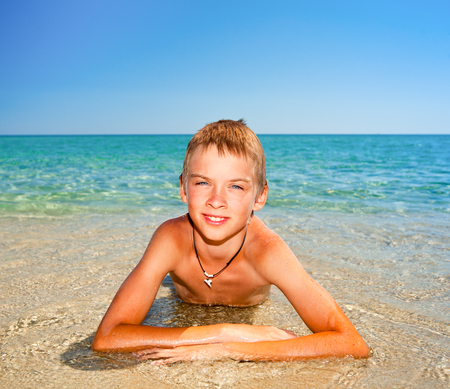Happy boy enjoying summer day on a beachの写真素材