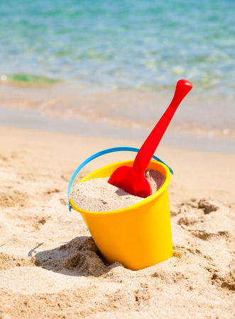 Yellow sand pail and shovel on a beachの写真素材