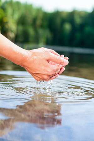 Woman taking clear water at a lake by handsの写真素材