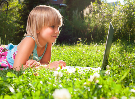 Little girl usng laptop in a summer gardenの写真素材