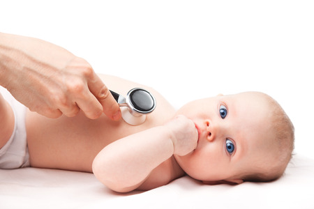 Close-up shot of pediatrician examines three month baby girl. Doctor using a stethoscope to listen to baby's chest checking heart beat. Child is looking at camera sucking hand.の写真素材
