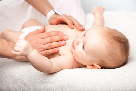 Three month baby girl is receiving chest massage from a female massage therapistの写真素材