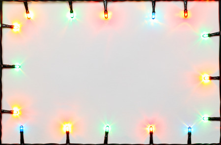 Christmas lights of different colors frame on white backgroundの写真素材