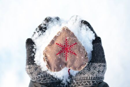 Woman wearing knitted mittens holding heart in cupped hands St. Valentine conceptの写真素材