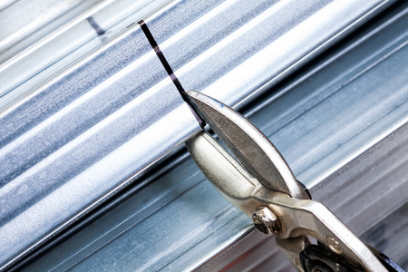 Person cuts a metal stud with snip cutter while constructing plasterboard frameの写真素材