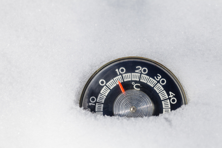 Vintage thermometer with celsius scale showing low temperature placed in fresh snowの写真素材