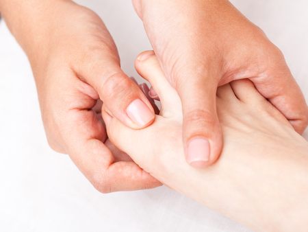 Young woman's foot finger being manipulated by osteopathic manual therapist or physicianの写真素材
