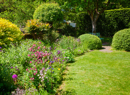 Green summer walled english formal garden with lawn blooming flowers and hedgerow in background, Southern England, UKの写真素材