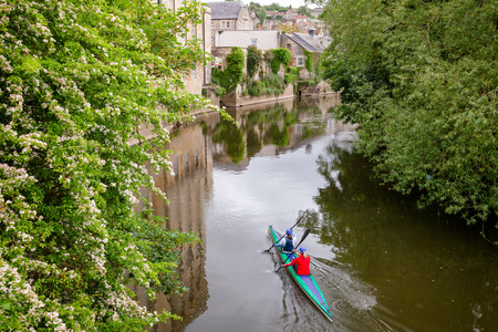 Two women kayaking down the River Avon (Bristol Avon) along scenic Bradford-on-Avon, a town and...