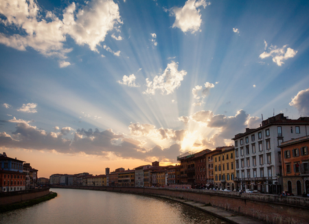 Pisa cityscape with dramatic sunset over medieval waterfront buldings on Arno River embankment, Tuscany, Italyの写真素材