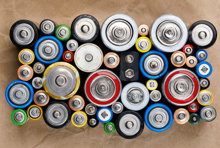 Used Alkaline batteries of various types (C AA AAA D 9V) on recycled paper ready for recycling - toxic waste and environmental issues conceptの写真素材