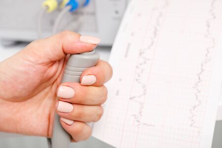 Close-up shot of pregnant woman's hand holding controller of the Cardiotocograph machine aka...