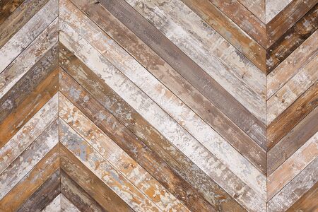 Wall decorated by wooden planks with peeled paint folded herringbone textured background