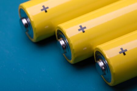 Close up shot of yellow AA alkaline or rechargeable NiMH batteries on blue background, shallow focusの写真素材