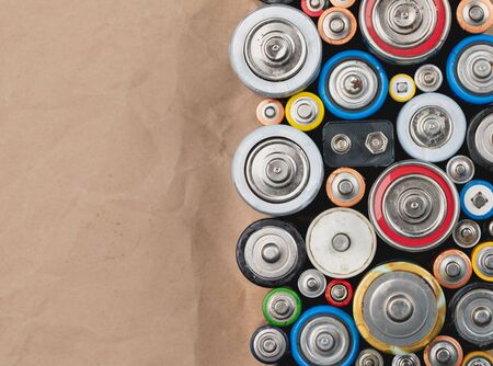 Used Alkaline batteries of different types (C AA AAA D 9V) on wrinkled recycled paper sorted for recycling - toxic waste and environmental issues backgroundの写真素材