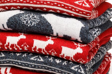 Stack of folded knitted Christmas turtleneck sweaters or pullovers with nordic ornament close-up shotの写真素材