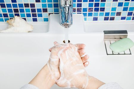 Child diligently washing hands with antibacterial soap and water performing basic protective...