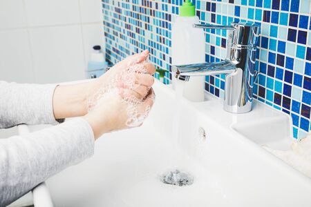 Child diligently washing hands with antibacterial soap and water performing basic protective measures against spreading of coronavirus COVID-19 deseaseの写真素材
