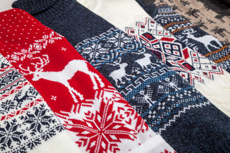 Various warm seasonal Christmas jumpers aka Ugly sweaters with deer and snowflake ornament laid foldedの写真素材