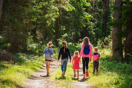 Little girls walking along a trail through summer forest enjoying warm sunny day- summer holidays conceptの写真素材