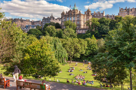 Edinburgh, UK - Aug 9, 2012: Locals and tourists enjoy warm sunny summer day relaxing and picnicking at the Princes Street Gardens, a famous public park in the city centerのeditorial素材