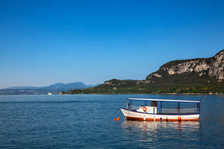 Pleasure boat moored near resort town on the eastern shore of Lake Garda in Northern Italy. Lake Garda is the largest lake in Italy and a popular holiday location on the edge of the Dolomitesの写真素材