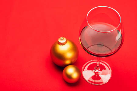 Glass of red wine with christmas baubles on red background - christmas drink conceptの写真素材