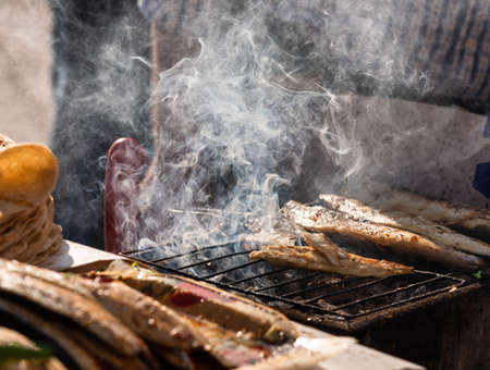 Vendor roasting mackerel fish on grill at Istanbul, Turkey, making a traditional turkish street food...