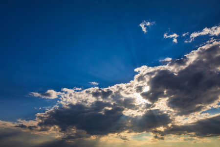 Dramatic evening sky with beams of sun rays shining throughの写真素材