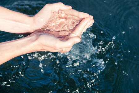 Person scoops up raw water from a lake. Natural water resources environmental awareness concept