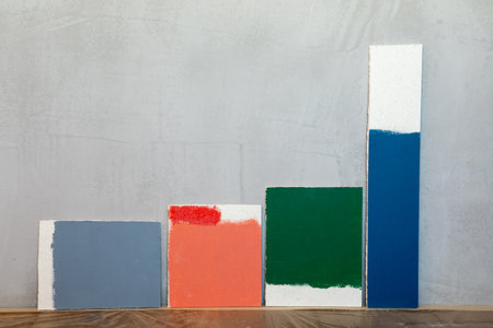 Grey red green and blue color samplers at blank gypsum plaster wall. Choosing wall paint color...