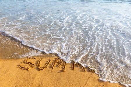 Wave washing away the handwritten inscription Summer on a sandy beachの写真素材