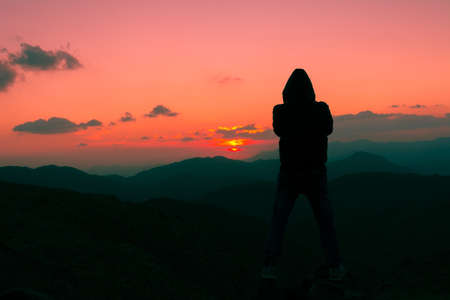 Beautiful mountain sunset with dramatic clouds and young boy's silhouette, Located in Banisad, Saudi arabiaの写真素材