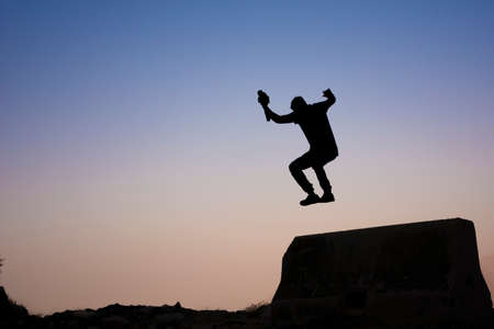 Jumping silhouette of photographer with sunset backgroundの写真素材