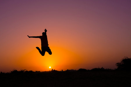 The silhouette of people jumping with sunset background,concept of happiness, joy, joyful lifeの写真素材