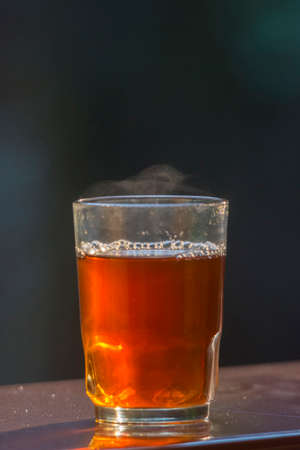 Freshly brewed black tea in a transparent glass Cup,escaping steam, Nature backgroundの写真素材