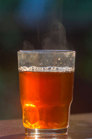 Freshly brewed black tea in a transparent glass Cup,escaping steam, Nature backgroundの写真素材