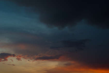 Beautiful scenery of black, dark blue and orange clouds in evening after heavy rainfall.