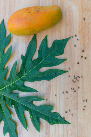 Fresh papaya fruit on wooden table with green leafの写真素材