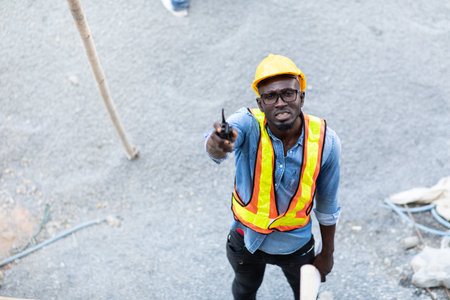 african american businessman  in protective safety hard hat looking at blueprint plans on construction site.の素材 [FY310162694157]