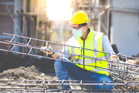 Asian construction worker on building site. fabricating steel reinforcement bar. wearing surgical...