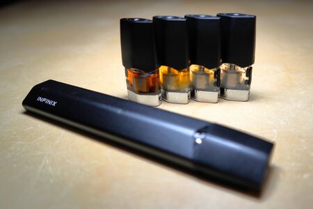 Smok Infinix refillable pod vape pen electronic cigarette with pods filled with e-juices of different shades of orange arranged in a gradient, isolated close upのeditorial素材