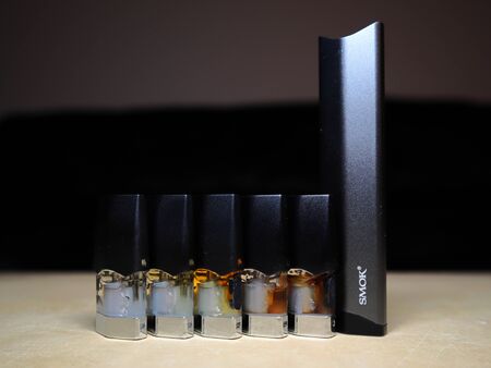 Smok Infinix refillable pod vape pen electronic cigarette with pods filled with e-juices of different shades of orange arranged in a gradient, isolated close upのeditorial素材